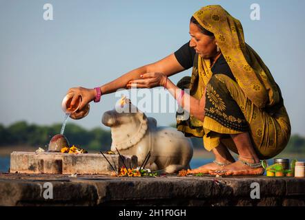 MAHESHWAR, INDIA - APRILE 26: La donna indiana suona la pooja mattina sul fiume sacro Narmada ghats il 26 aprile 2011 a Maheshwar, Madhya Pradesh, India. Foto Stock