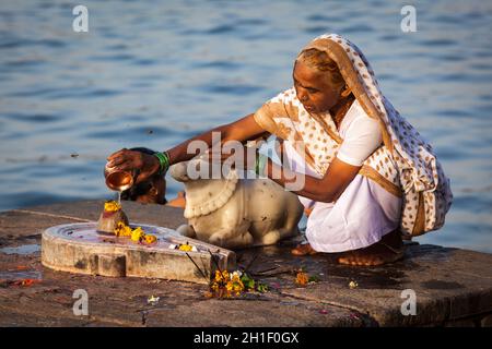 MAHESHWAR, INDIA - APRILE 26: La donna indiana suona la pooja mattina sul fiume sacro Narmada ghats il 26 aprile 2011 a Maheshwar, Madhya Pradesh, India. Foto Stock