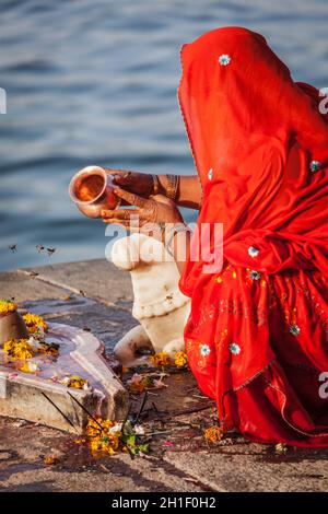 MAHESHWAR, INDIA - APRILE 26: La donna indiana suona la pooja mattina sul fiume sacro Narmada ghats il 26 aprile 2011 a Maheshwar, Madhya Pradesh, India. Foto Stock