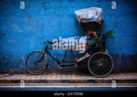 DELHI, INDIA - 11 SETTEMBRE 2011: Il driver indiano del rickshaw del ciclo che dorme sulla sua bicicletta nella strada di Nuova Delhi, India. Sono stati utilizzati risciò ciclicci Foto Stock