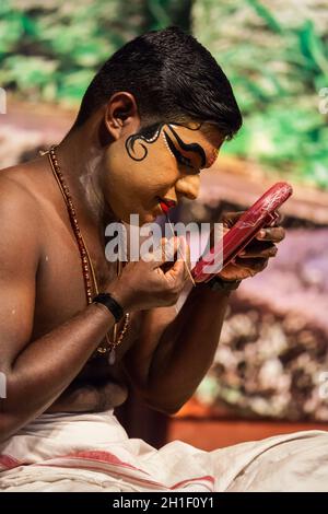 KOCHI, INDIA - 24 FEBBRAIO 2013: Esponente di Kathakali non identificato che si prepara per la prestazione applicando il make-up del volto. Kathakali è la danza classica Foto Stock