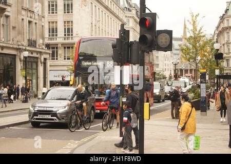 Ciclisti, pedoni, auto e un autobus che attende al semaforo di Oxford Circus nel centro di Londra Foto Stock