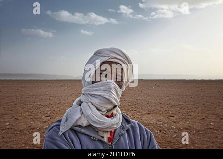 Un beduino non identificato uomo indossa abbigliamento tradizionale nel deserto del Sahara. Bedouin sono una parte di una prevalenza di deserto arabico gruppo etnico Foto Stock