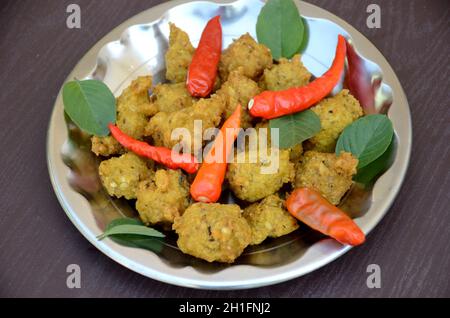 Closeup il mazzo giallo marrone bengala grammo fritto cibo con peperoncino rosso e menta verde nel piatto Foto Stock