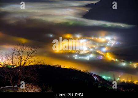 Luci di città sotto la fitta nebbia della valle Padana, provincia di Vicenza, Italia Foto Stock