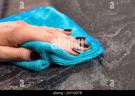 Pulizia del piano di lavoro. Cura dei countertops nella cucina o nella stanza da bagno. Pulizia di superfici in pietra, marmo o pietra artificiale. Salviette per le mani da donna Foto Stock