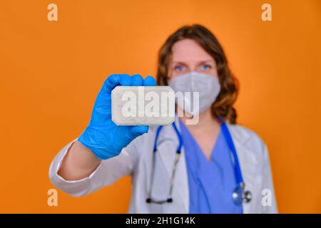 Medico donna che tiene un sapone bianco su uno sfondo rosso, primo piano. Foto Stock