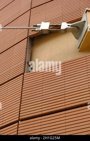 Tiranti in acciaio e facciata in mattoni. Edificio moderno coperto di pianelle in terracotta. Lodi, Lombardia, Italia. Foto Stock