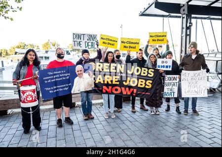 Washington, Stati Uniti. 18 Ott 2021. I manifestanti tengono striscioni e cartelli che esprimono la loro opinione durante la protesta. Una protesta contro le posizioni legislative che il senatore americano Joe Manchin (D-WV) ha assunto riguardo al pacchetto di riconciliazione di bilancio. La protesta ha avuto luogo vicino al molo dove la barca del senatore è ancorata a Washington, DC Credit: SOPA Images Limited/Alamy Live News Foto Stock