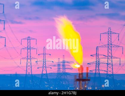Piloni elettrici all'alba con camino a gas per impianti industriali/chimici. REGNO UNITO. Gas crescente, elettricità, energia.., prezzi, riscaldamento globale, concetto Foto Stock