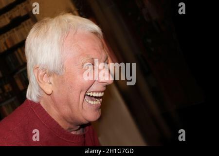 Profilo di un bell'uomo ridente con capelli grigi a casa. Concetto di emozioni umane Foto Stock