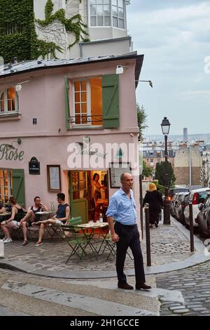 Parigi, Francia - Luglio 2019: I turisti stanno bevendo e cenando sulla terrazza del ristorante la Maison Rose in rue Girardon a Montmartre, su somma Foto Stock