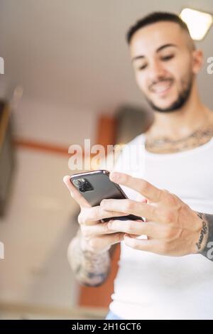 Messa a fuoco superficiale verticale di un giovane che controlla il suo telefono Foto Stock