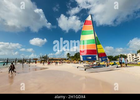 Bridgetown, Barbados - December 18, 2016: Brownes beach at ocean coast with people and colorful sail on a yacht at sunny day in Bridgetown, Barbados. Foto Stock