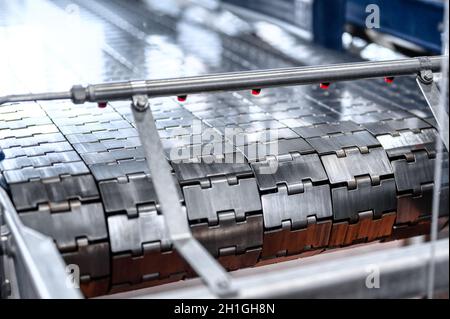 Nastro trasportatore industriale in metallo. Il nastro è costituito da piastre metalliche Foto Stock