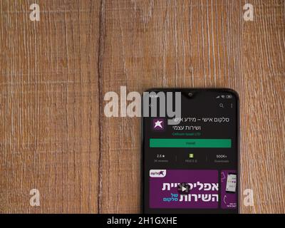 LOD, Israele - 8 luglio 2020: Pagina del negozio dell'app Cellcom sul display di uno smartphone nero su sfondo di legno. Vista dall'alto piatta con copia Foto Stock