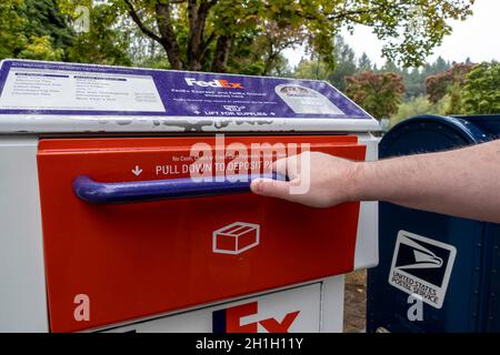 Kirkland, WA USA - circa Settembre 2021: Vista angolata di una mano tirando aprire un pacchetto FedEx e la porta della stazione di deposito lettera nel centro di Kirkland Foto Stock