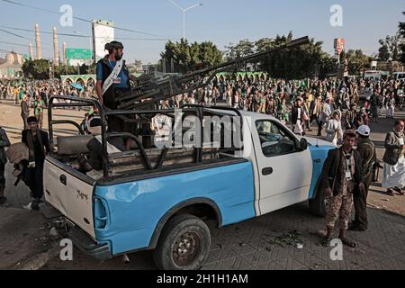 Sanaa, Yemen. 18 Ott 2021. Un uomo si alza vicino a una mitragliatrice su un veicolo, mentre i ribelli Houthi e i loro sostenitori si riuniscono per una celebrazione che segna l'anniversario della nascita del profeta dell'Islam Muhammad (Mawlid al-Nabi) a Sanaa. Credit: Hani al-ANSI/dpa/Alamy Live News Foto Stock