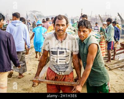Chittagong, Bangladesh, 23 dicembre 2017: Ritratto dei pescatori che tirano il carrello con la cattura fresca di gamberetti Foto Stock