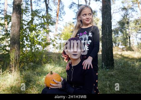 Due sorelle felici nella foresta di Halloween. Divertenti bambini in costumi di carnevale all'aperto a Halloween trick o delizia. Buon Halloween! Foto Stock