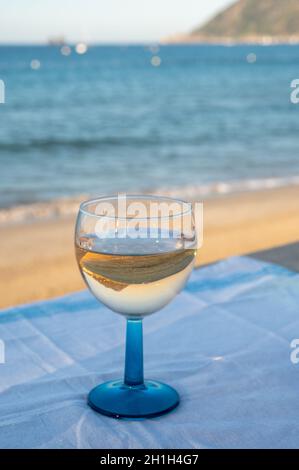 Estate in Provenza, bere di vino rosato secco freddo gris sulla spiaggia di sabbia e mare blu vicino Tolone, dipartimento del Var, Francia Foto Stock