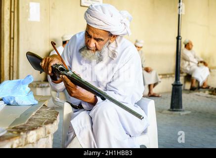 Nizwa, Oman, 2 dicembre 2016: Un anziano sta ispezionando un fucile da caccia al mercato delle armi del venerdì a Nizwa, Omam Foto Stock