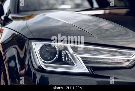 Foto ravvicinata del faro su auto grigio scuro. Foto Stock