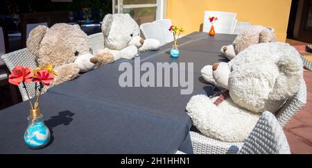 Un gruppo di orsi Teddy seduto al tavolo e pronto per un pranzo o una riunione Foto Stock