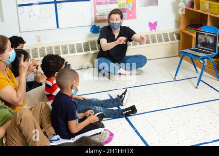 Istruzione Preschool 4-5 anni di musica sessione fatta da remoto sopra zoom bambini e insegnanti seguendo insieme con canzone con gesti della mano Foto Stock