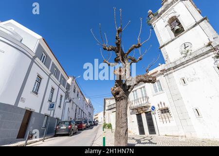 Sesimbra, Portogallo - 19 febbraio 2020: Dettaglio architettonico di una piccola strada nel centro della città con la sua chiesa in un giorno d'inverno Foto Stock