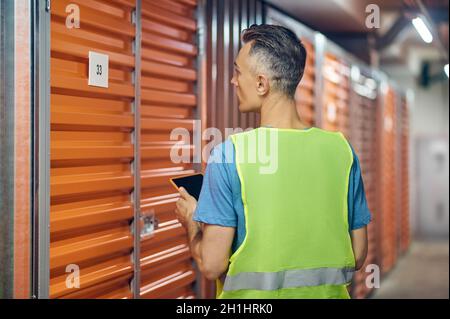 Uomo che lavora in una guardia di magazzino in piedi con la schiena Foto Stock