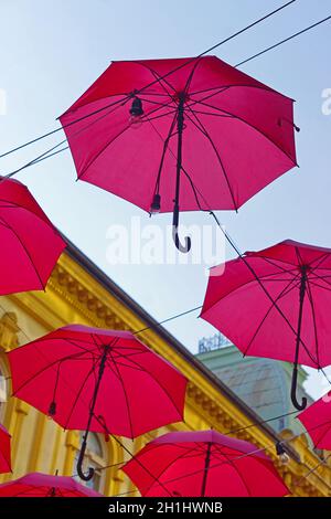 Molti open red umberllas overhead decor di strada Foto Stock