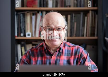 Uomo anziano a casa di fronte al computer portatile Foto Stock