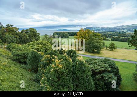 Vista attraverso i giardini verso l'isola di Menia dritto e puffin dal castello di Penrhyn, una casa di campagna normanna a Llandygai, Bangor, Galles del Nord Regno Unito Foto Stock