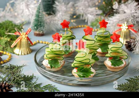 Tartine festive a forma di alberi di Natale in cetrioli e stelle di peperone su sfondo azzurro Foto Stock