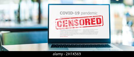 Computer portatile che mostra il segno di censura su Internet sito con covid-19 informazioni pandemiche Foto Stock