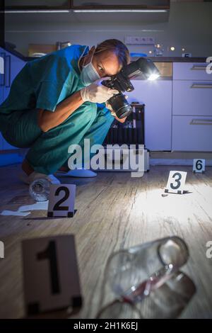 Specialista forense in tuta protettiva per scattare delle foto su una scena del crimine Foto Stock