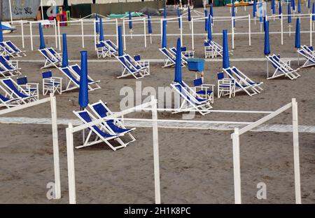 Ombrelloni e sedie da spiaggia tipici italiani a Viareggio, uno dei luoghi di villeggiatura italiani più famosi d'estate Foto Stock