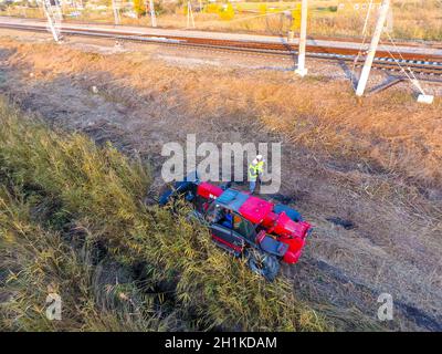 Slavyansk-on-Kuban, Russia - 12 ottobre 2017: Il bulldozer libera lo spazio lungo le piste ferroviarie. Rastrellatura di canne da bulldozer. Foto Stock