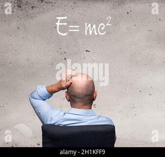 un uomo che legge la formula della relatività scritta su un muro Foto Stock