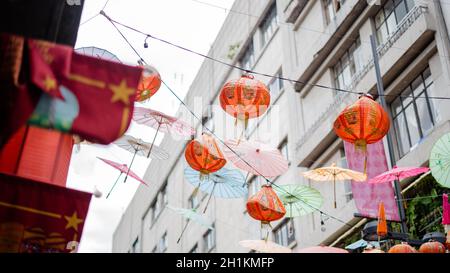 Foto di lampade cinesi tradizionali rosse che si aggettano dai cavi in un vicolo Foto Stock