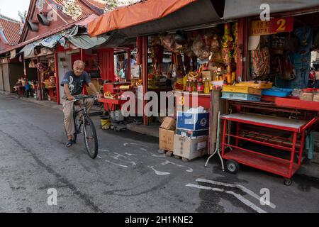 George Town, Penang/Malesia - Luglio 19 2018: Un vecchio ciclo di uomo vicino al bastone di vendita di joss di stallo, carta di joss al tempio di Goddess of Mercy. Foto Stock