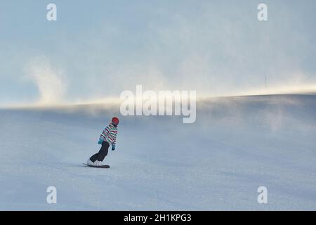 Snowboarder in discesa, vento che soffia neve all'orizzonte Foto Stock