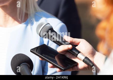 Giornalisti che fanno un'intervista stampa con businesswoman o uomo politico femminile Foto Stock