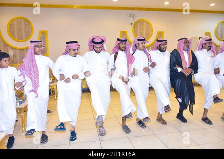 2020 luglio, sala matrimoni Riyadh, Arabia Saudita, uomini sauditi celebrare e godersi la danza tradizionale con oggetti culturali in mano durante l'evento di nozze Foto Stock