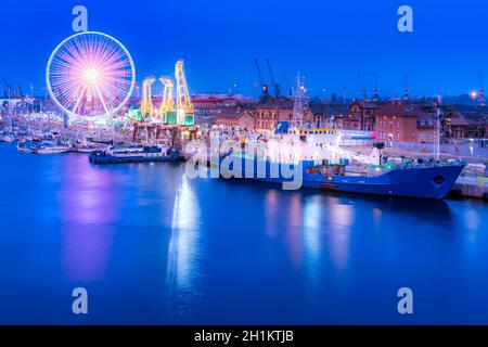 Navi, gru chiamato Dzwigozaury e parco di divertimenti a Odra River Boulevards a Szczecin. Folle che si godono giorni del mare. Foto notturna a lunga esposizione Foto Stock