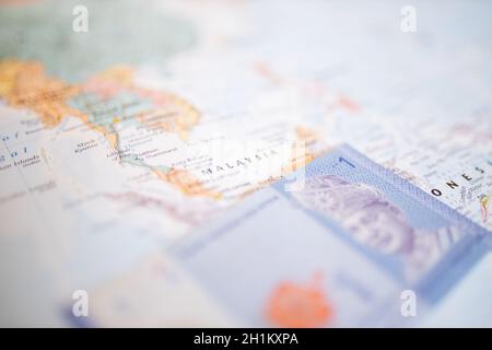 Primo piano di una banconota da ringgit malese sotto la Malesia su una mappa colorata dell'Asia con il resto dei paesi sfocati Foto Stock