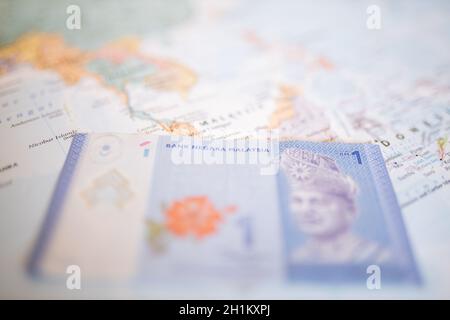 Primo piano di una banconota da ringgit malese sotto la Malesia su una mappa colorata dell'Asia con il resto dei paesi sfocati Foto Stock