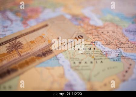 Dieci banconote da riyal Saudita sopra l'Arabia Saudita su una mappa colorata del Medio Oriente Foto Stock