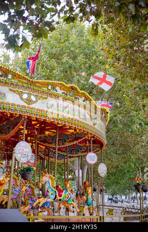 Ritratto Vista di una colorata giostra per bambini circondata dagli alberi di un parco da Londra, Regno Unito Foto Stock